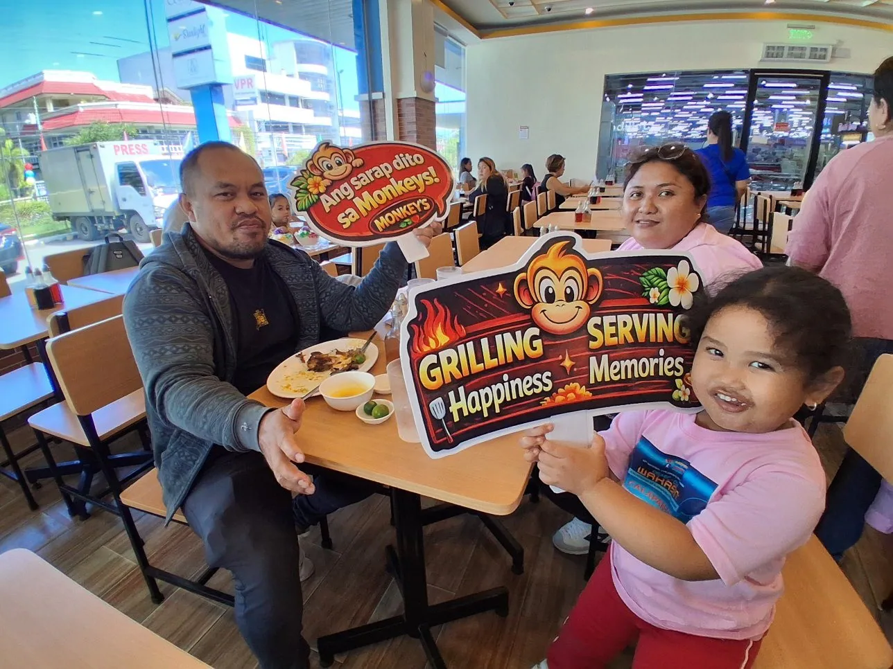 Family enjoying a meal by the window at Monkey's Resto